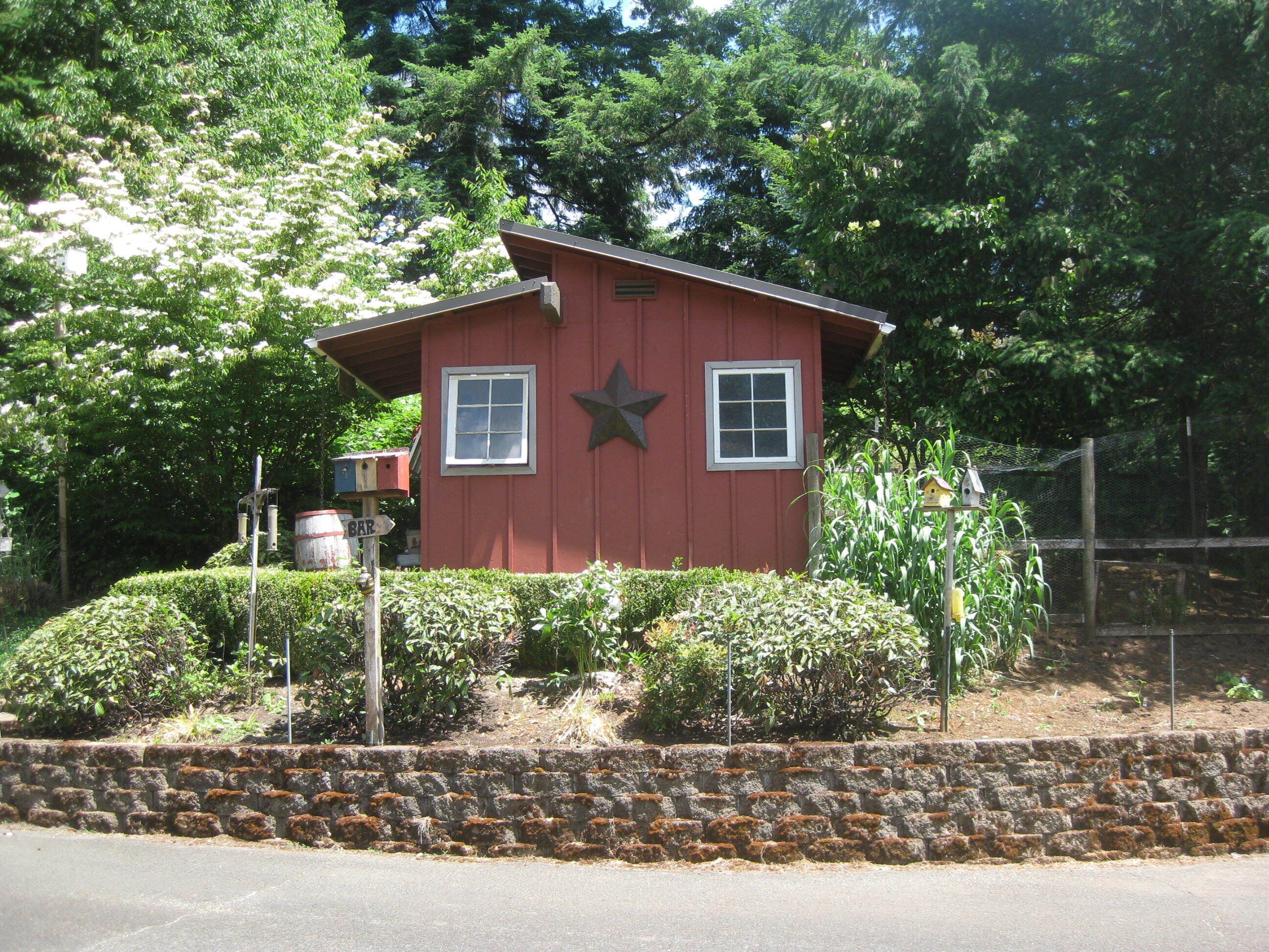 Un edificio rojo con una estrella en la pared, una ventana y un pequeño jardín.