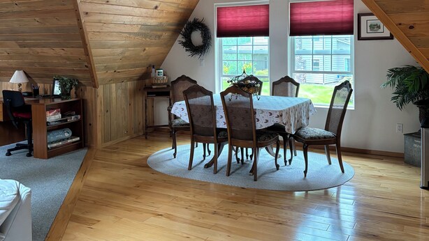 Un comedor con una mesa redonda, sillas de madera y techo con vigas a la vista.