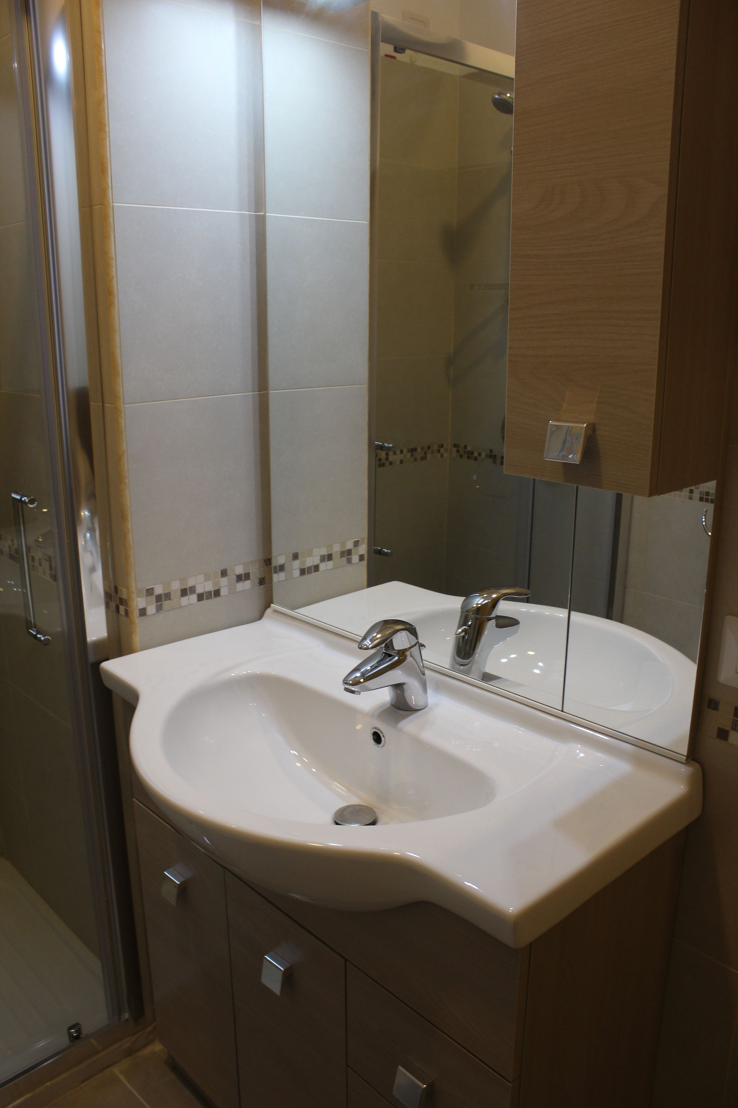 A bathroom with a white sink, a mirror, and a shower.