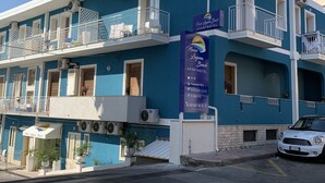 Un edificio a due piani con balconi, condizionatori e un cartello che indica Naxos Laguna Beach Apartments.
