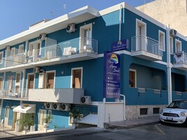 A two-story building with balconies, air conditioning units, and a sign for Naxos Laguna Beach Apartments.
