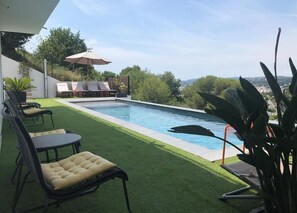 A pool area with artificial grass, lounge chairs, and a view of the landscape. - Twenty Rent (Cagnes-sur-Mer)
