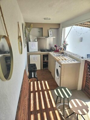 A compact kitchenette with a stove, microwave, and sink, a washing machine, and a small dining area with a table and chairs. - Twenty Rent (Cagnes-sur-Mer)