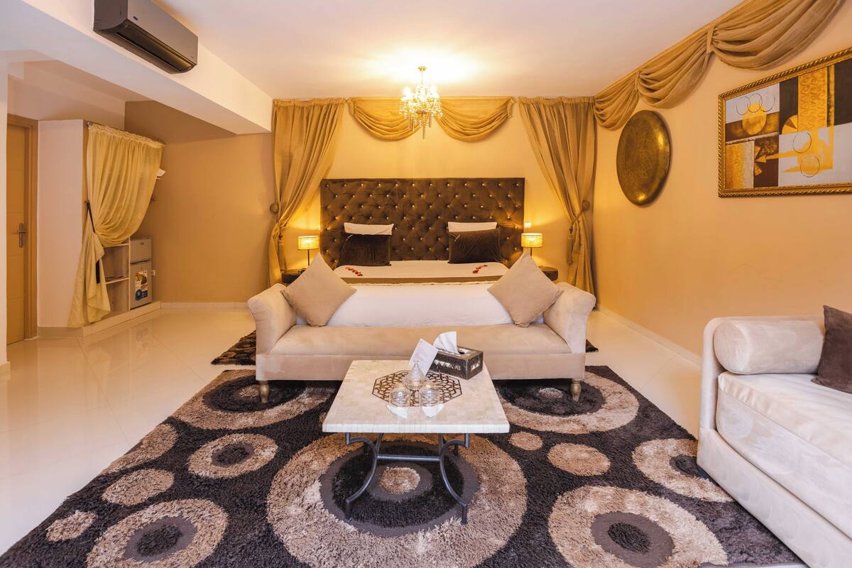 Habitació d'hotel amb un llit gran, dues taules de nit, un sofà i una taula de centre.