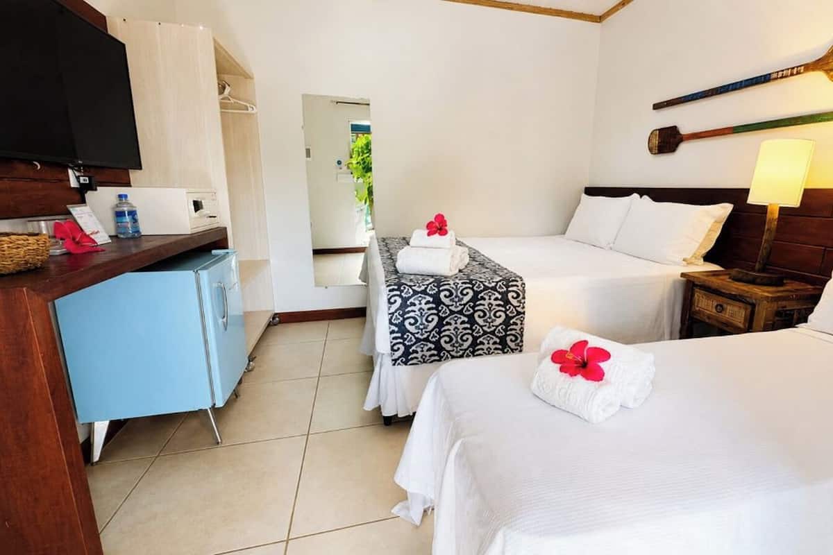 A hotel room with two beds, a desk, a TV, and a mirror.