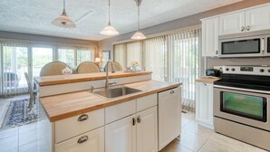 A kitchen with white cabinets, a wooden countertop, a sink, a microwave, and an oven. - Island Life!  Kent Island Waterfront with Pool-Bring your boat! (Stevensville)