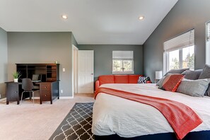 Een slaapkamer met een groot bed, een bureau en een stoel.