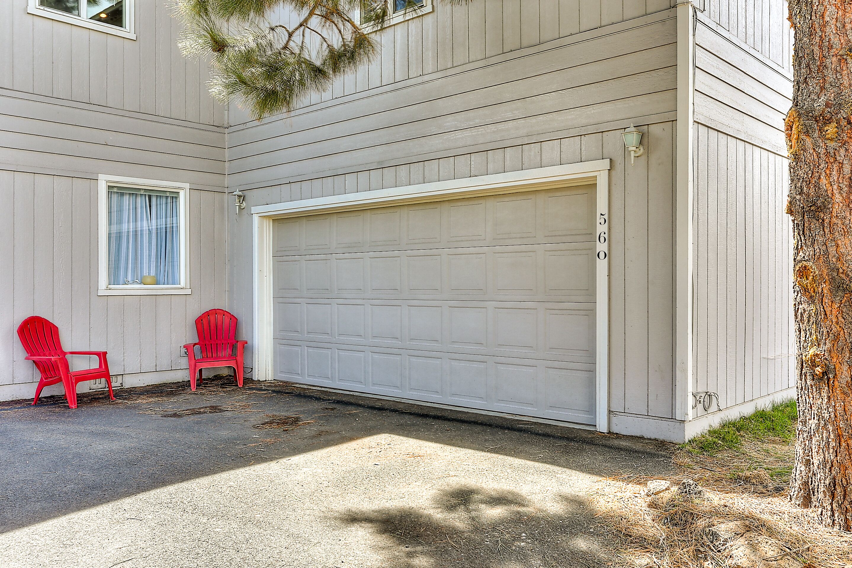 A garage door, two red chairs, and a tree.