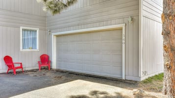 A garage door, two red chairs, and a tree.