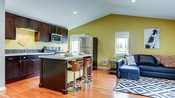 A modern kitchen with dark wood cabinets, a stainless steel refrigerator, and a bar stool area.