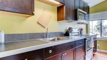 A modern kitchen with dark wood cabinets, a stainless steel sink, and a built-in microwave.