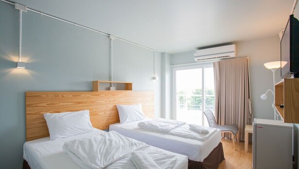 A hotel room with two beds, a desk, a chair, an air conditioner, and a TV. - Comfy accom. 2(BTS Saphan Khwai) (Bangkok)