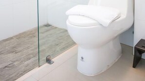 A modern bathroom with a glass-enclosed shower, a white toilet, and a small bedside table. - Comfy accom. 2(BTS Saphan Khwai) (Bangkok)
