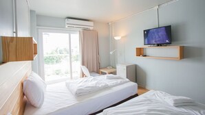 Una camera d'albergo con un letto, una TV, una scrivania e una finestra con tende.