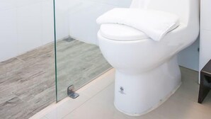 Un bagno moderno con cabina doccia in vetro, un water bianco e una piccola finestra.