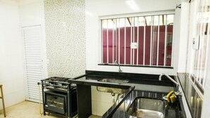Une cuisine équipée d’une cuisinière à gaz, d’un évier et d’une fenêtre avec des barreaux.