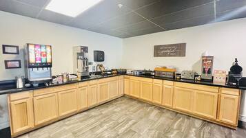 Una cocina con cafetera, refrigerador y un cartel en la pared.