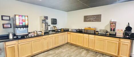 A kitchen with a coffee machine, a refrigerator, and a sign on the wall.