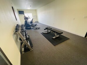 A gym with exercise equipment, including dumbbells, a bench, and cardio machines.