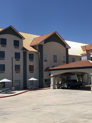 A multi-story building with a covered parking area and outdoor seating.