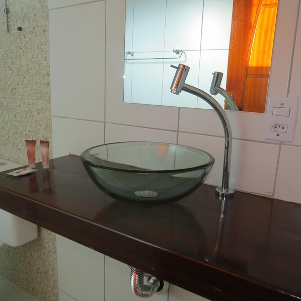 A modern bathroom with a glass bowl sink, a stainless steel faucet, and a mirror above it. - Costa Dourada Pousada (Arraial do Cabo)