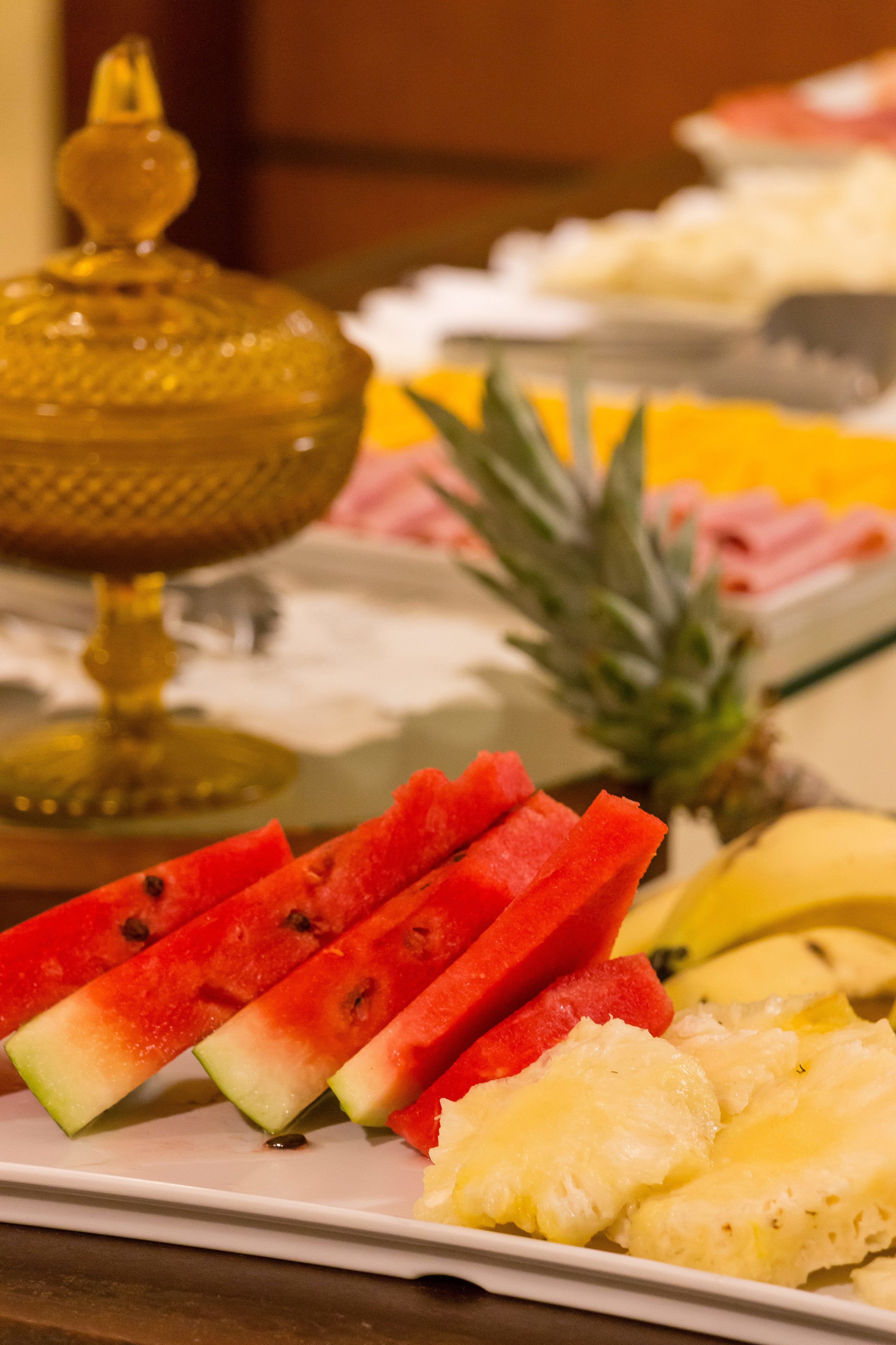 Uma tábua de frutas com melancia, abacaxi e fatias de banana.