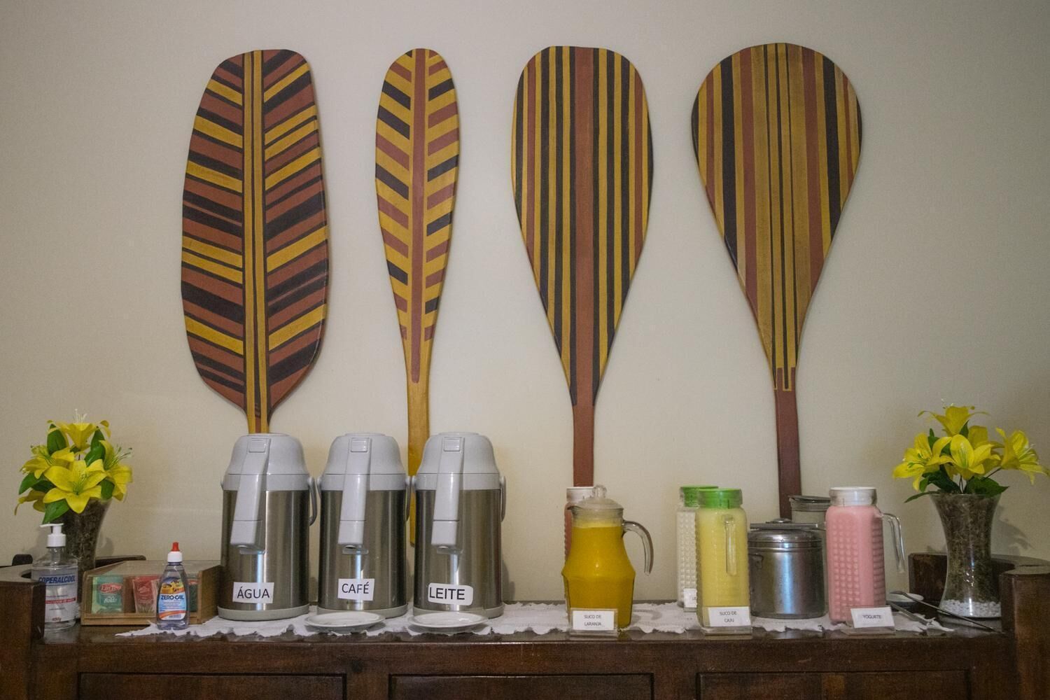 A wall with four wooden paddles and a row of beverage dispensers labeled with different drinks.
