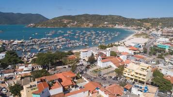 A coastal town with a marina filled with boats, buildings with red-tiled roofs, and a beach area.