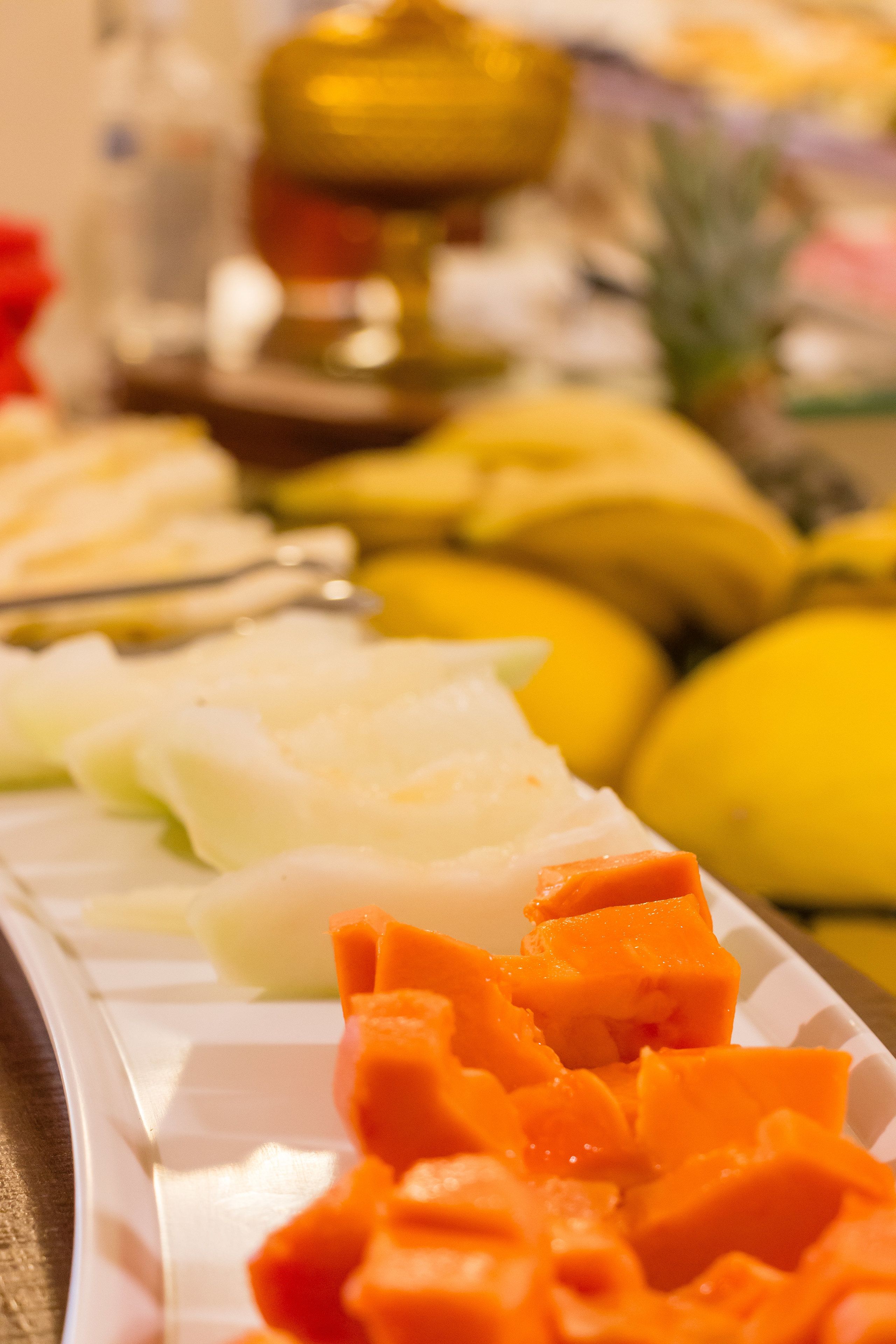 A buffet with various fruits and vegetables, including bananas and carrots.