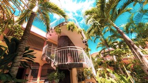 Ein tropisches Resort mit Innenhof, Palmen und einem mehrstöckigen Gebäude mit Balkonen.