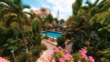 A pool surrounded by lush greenery and a multi-story building with balconies.