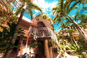 A multi-level building with balconies, surrounded by lush tropical vegetation.