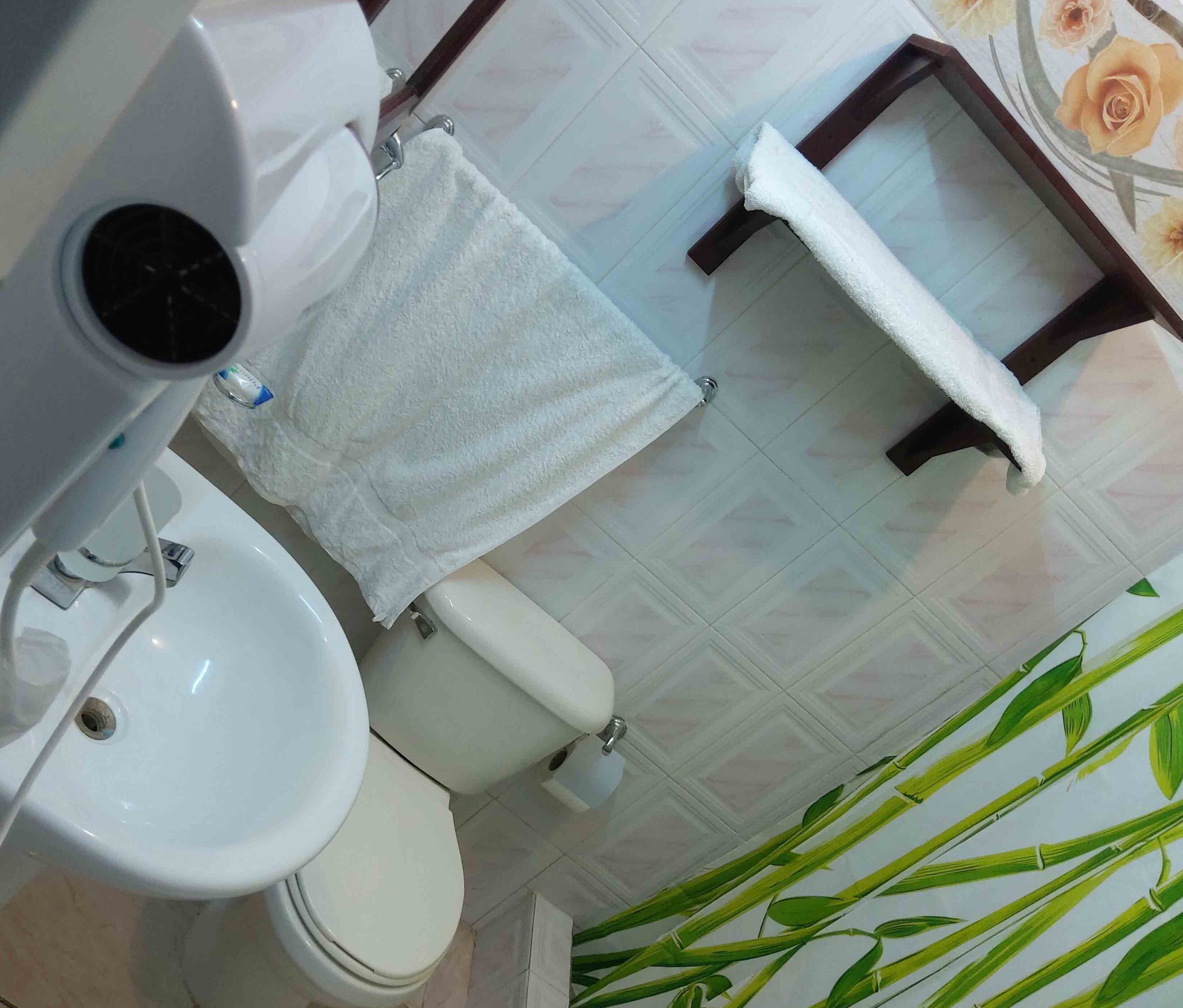 A bathroom with a toilet, bidet, and sink. A white towel is draped over the toilet.