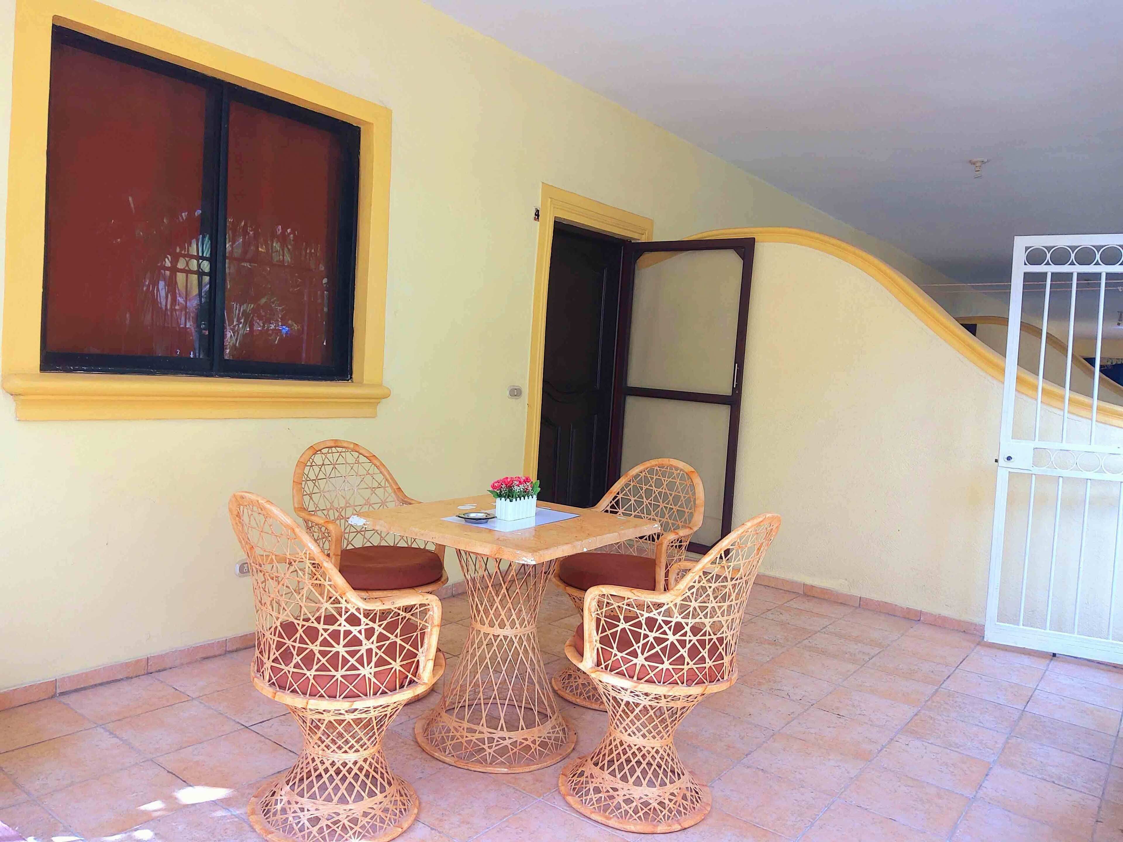 A dining area with wicker chairs and a table, a window, and a door.