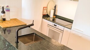 Een keuken met een granieten aanrecht, een spoelbak en een kookplaat.