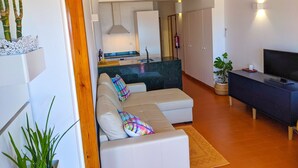 Een moderne woonkamer met een bank, een televisie en een keuken in de achtergrond.