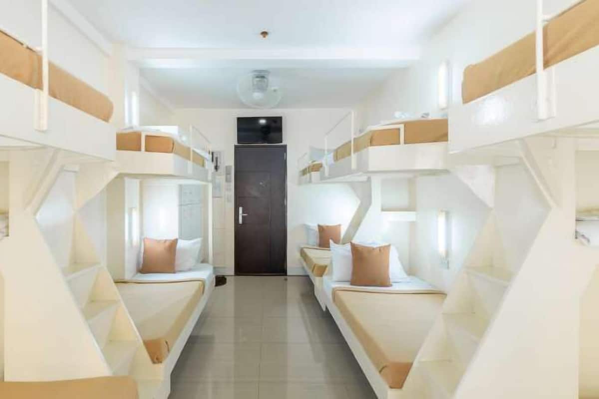 A corridor with bunk beds, a door, and a ceiling light.