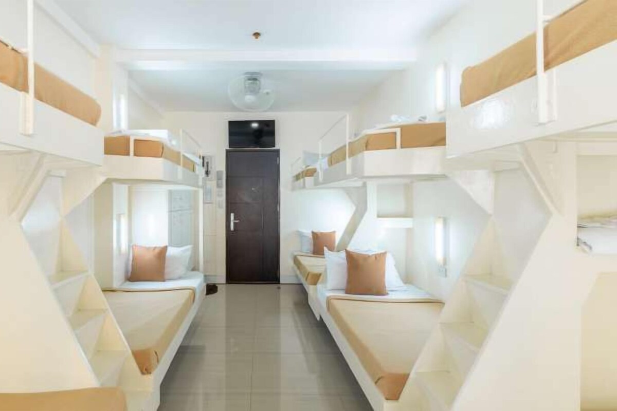 A corridor with bunk beds, a door, and a ceiling light.