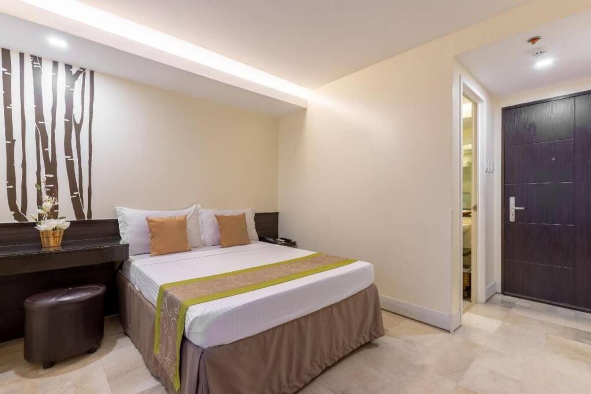 A hotel room with a bed, bedside table, lamp, and a door leading to a closet.