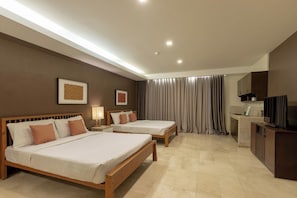 Quarto de hotel com duas camas, uma mesa de escritório com televisão e banheiro com cortina de chuveiro.