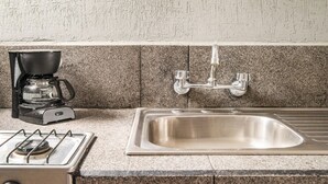 A kitchen with a gas stove, a coffee maker, and a stainless steel sink.
