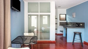 A modern kitchen with a built-in island, a dining area with a table and chairs, and a sliding glass door leading to a bedroom.