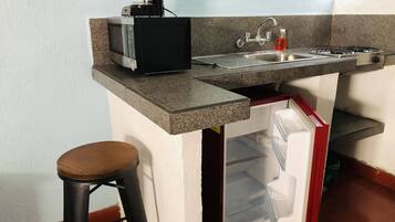 A compact kitchen with a microwave, coffee maker, sink, and a small refrigerator.