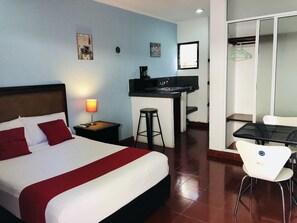 A hotel room with a bed, a desk with a sink, a chair, and a wardrobe. - Dpas 52 (Mérida)