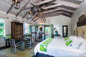 A room with a wooden ceiling, a bed with green and white bedding, a desk with a chair, and a window with curtains.