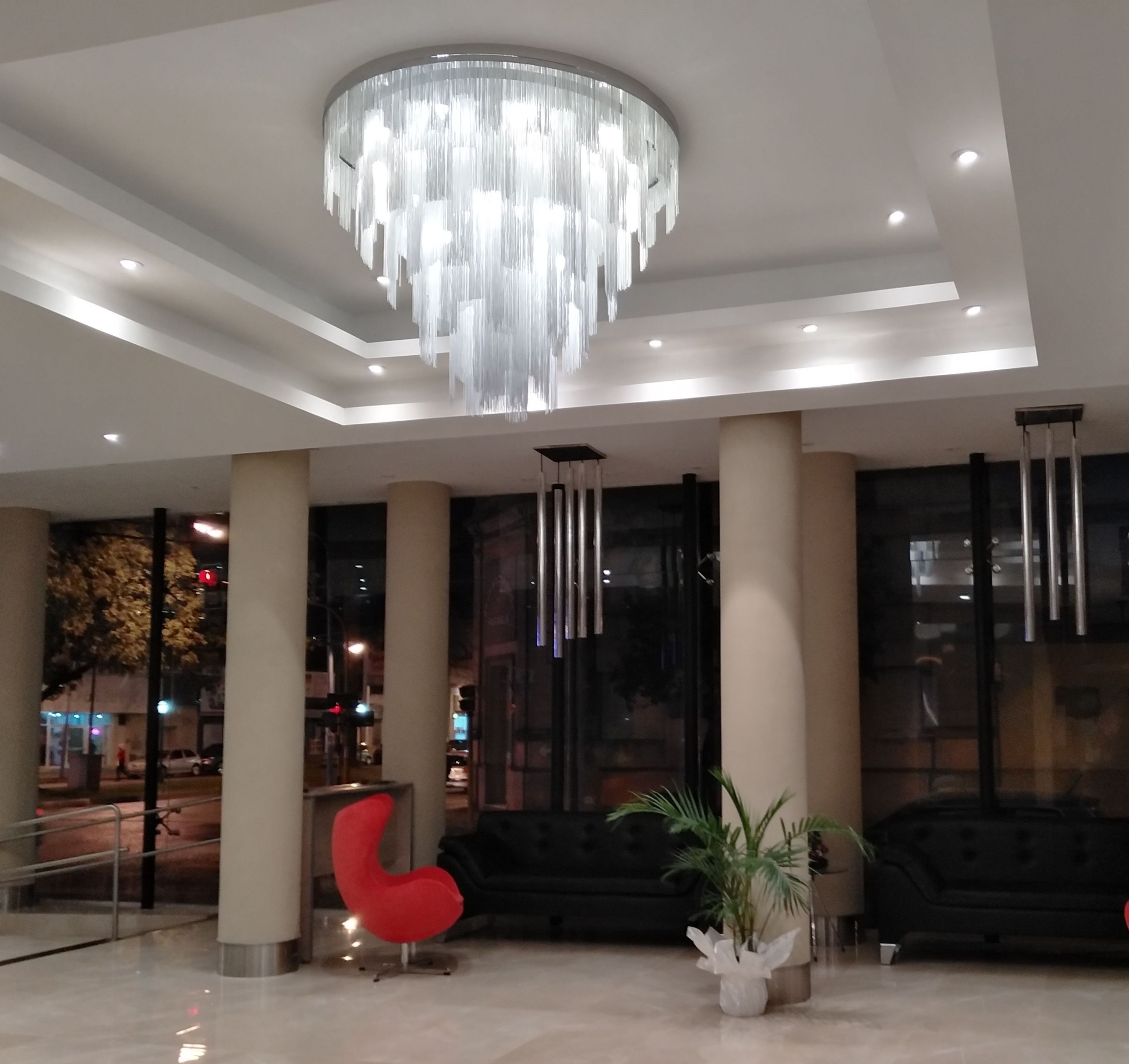 A modern lobby with a large chandelier, seating areas, and large windows.