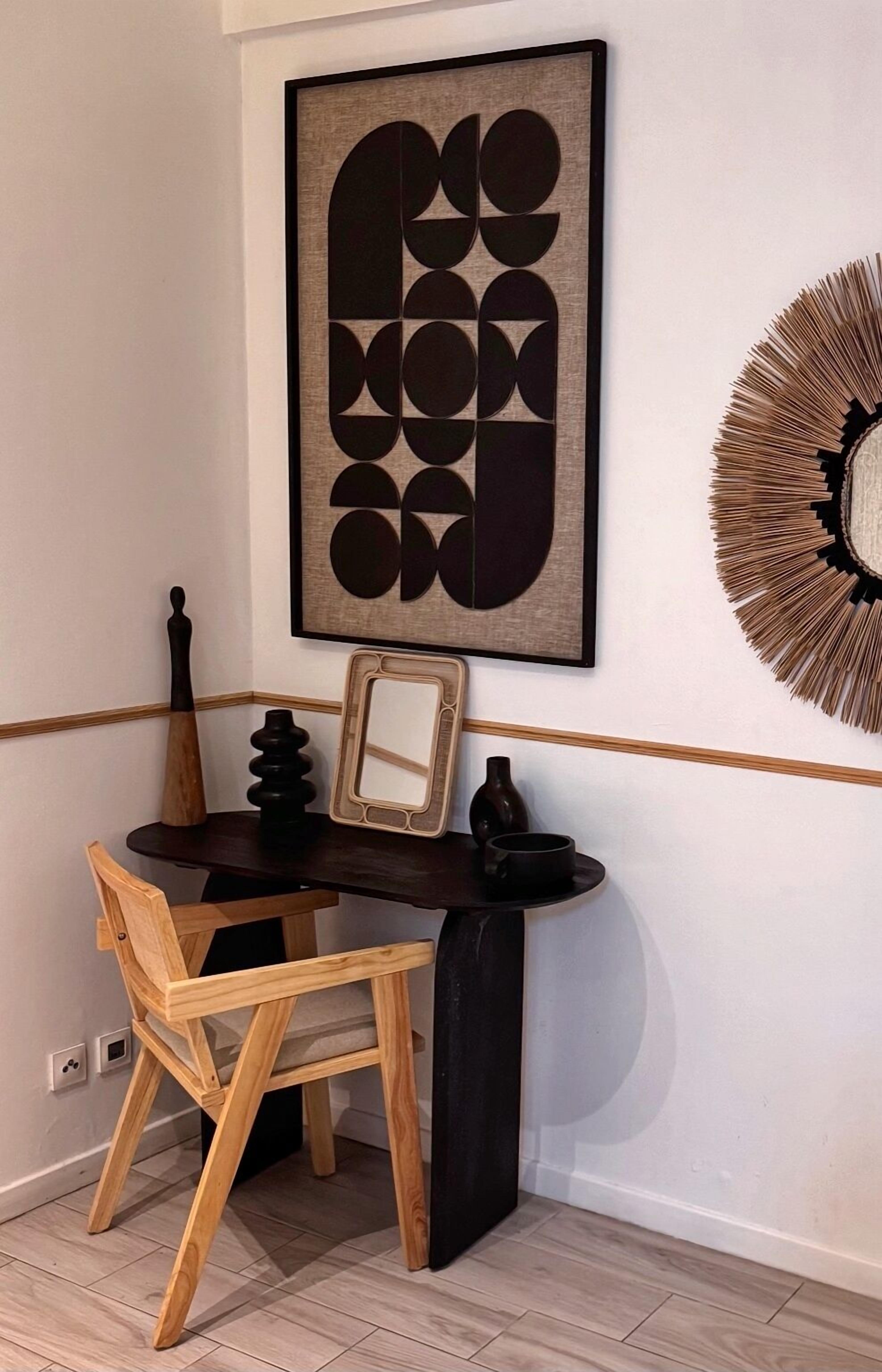 Une pièce d’angle avec un bureau en bois foncé, une chaise en bois, un miroir encadré, un élément décoratif mural et un miroir fixé au mur.