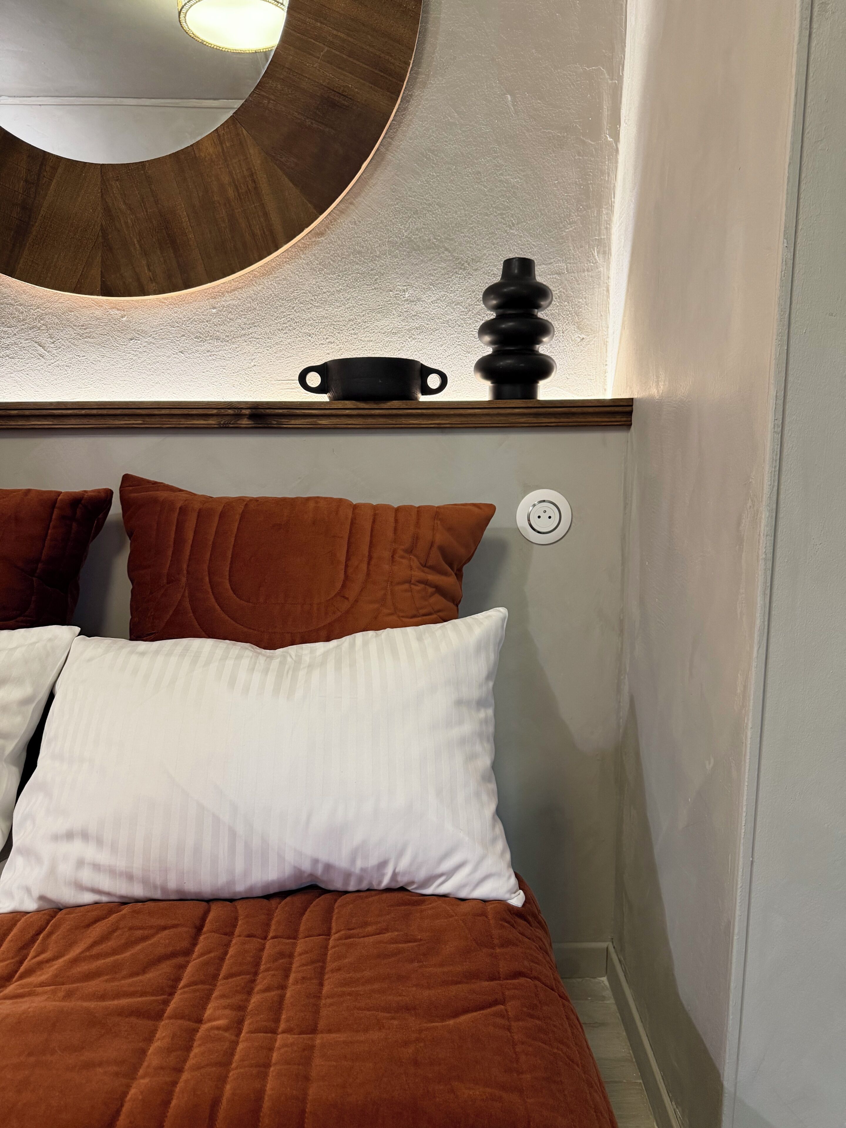 A bed with brown bedding, a white pillow, and a brown pillow.