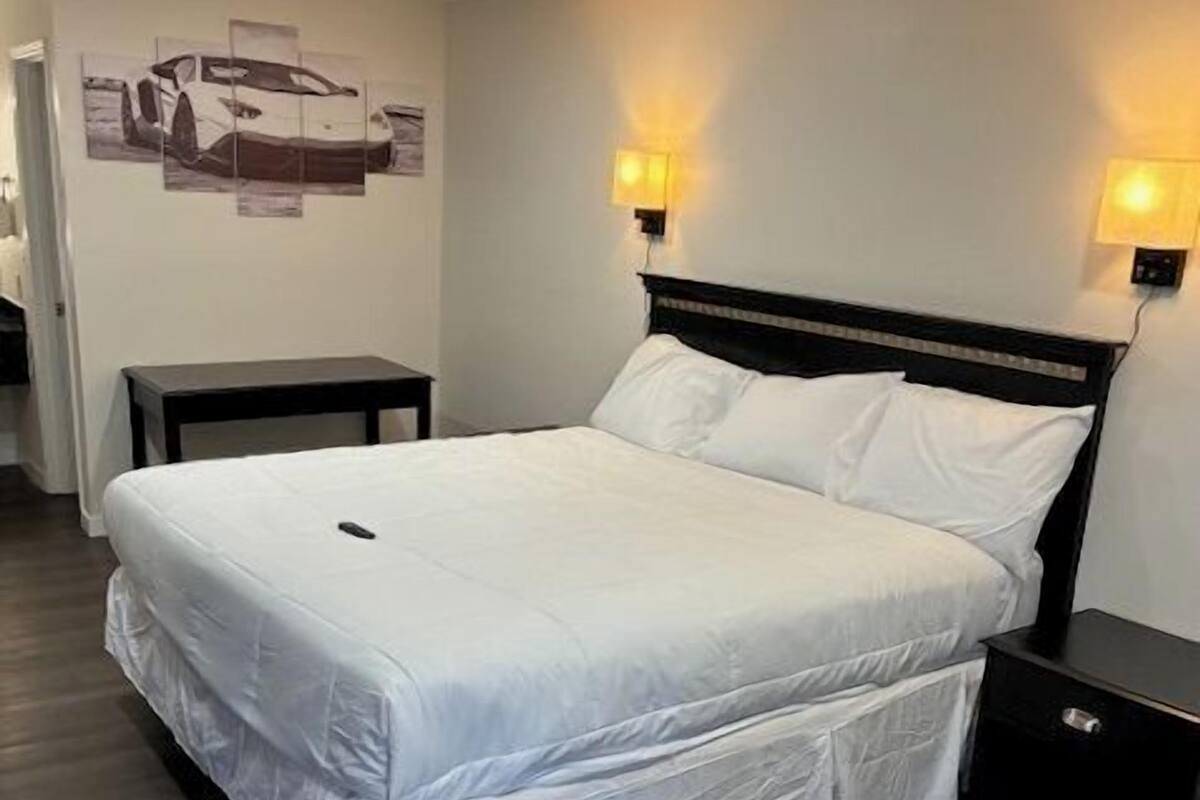 A neatly made bed with white linens in a hotel room.