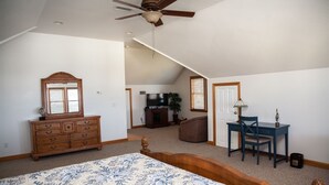 Une chambre à coucher avec un grand lit, un bureau, une chaise, une commode et un ventilateur de plafond.
